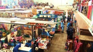 An indoor market in Nairobi with vendors selling flowers, crafts, and fresh produce, bustling with activity.